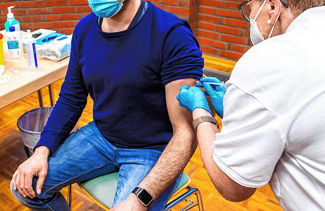 Ein Sportlehrer wird von einer Krankenschwester von einem mobilen Impfteam mit dem AstraZeneca-Impfstoff gegen Corona geimpft.