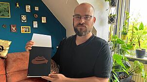 Jonas Fehlinger zeigt einen Abdruck seines Plakats in Kleinformat.