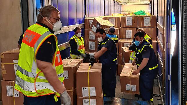 Helfer aus Frankfurt verladen gemeinsam mit THW-Kräften aus Waldshut-Tiengen Material aus einem Flugzeug aus China in die Lastwagen.