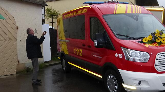 Pfarrer Erwin Roser tauft das neue Feuerwehrfahrzeug der Abteilung Fützen bei strömendem Regen.