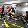 Knöcheltief stehen die Feuerwehrmänner im Wasser und montieren die Rohre einer Pumpe. Das Bild entstand im Untergeschoss im Parkhaus Post.