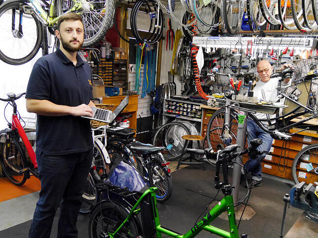 Zweiradmechaniker Sercan Degermenci vom Kulturrädle hat zur Datenanalyse einen Laptop an sein E-Bike angeschlossen. Im Hintergrund ...