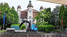 Der Fahrer eines LKW lädt mit seinem Kran die Gewichte für die Kino-Leinwand im Schlosspark Bad Säckingen ab.