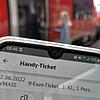 Ein Bahnfahrer hält im Bahnhof Waldshut ein Handy mit dem Neun-Euro-Ticket.