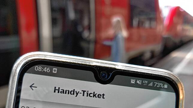 Ein Bahnfahrer hält im Bahnhof Waldshut ein Handy mit dem Neun-Euro-Ticket.