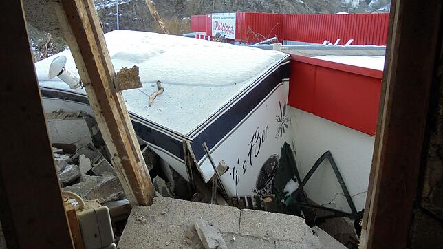 Von Schlamm und Geröll zerdrückt klemmt "Oli's 73er"-Imbisswagen auf dem Parkplatz beim Thomas Philipps-Markt an der Gebäudewand.