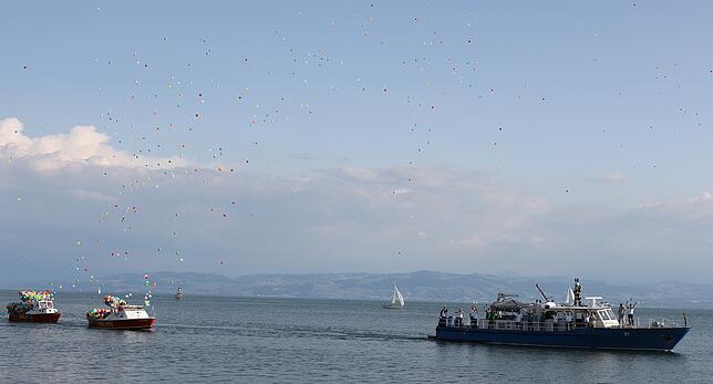 Der Seehas verschwindet mit dem Schiff wieder im See, wozu Hunderte von Luftballons aufsteigen.