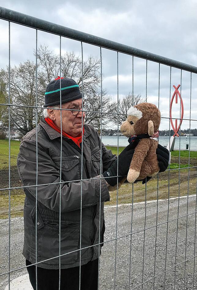 Der Künstler Johannes Dörflinger betrachtet einen Plüschaffen am Grenzzaun.