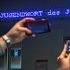 Auf einem Laufband erscheint „Jugendwort des Jahres“ über den digitalen Newsticker eines Hotels in München.