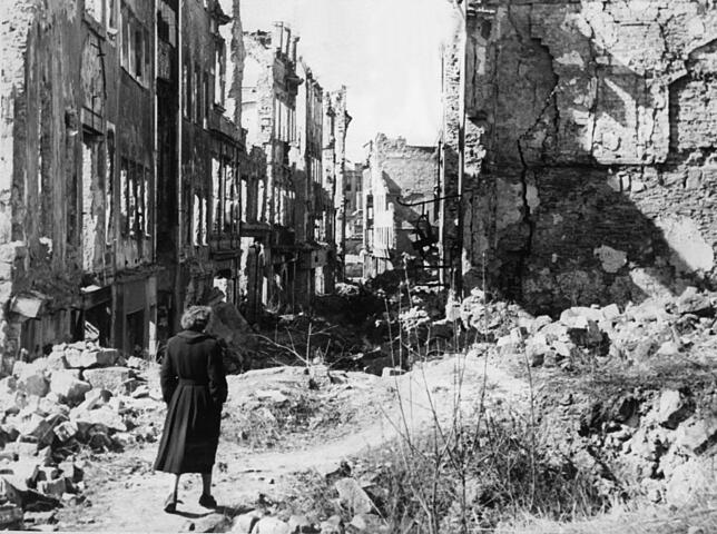 Eine Frau geht nach Kriegsende in einer Straße in Dresden an Häusern vorbei, von denen nach dem Bombenangriff am 13./14. Februar 1945 ...
