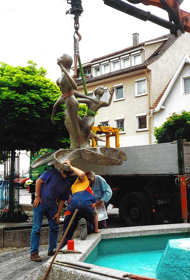 Die Brunnenskulptur schwebt im Jahr 2000 per Kran ein und wird dann auf den Brunnen montiert.