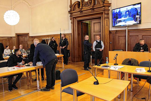 Zwei der Angeklagten, links und rechts vorne sitzend, beratschlagen sich mit ihren Verteidigern.