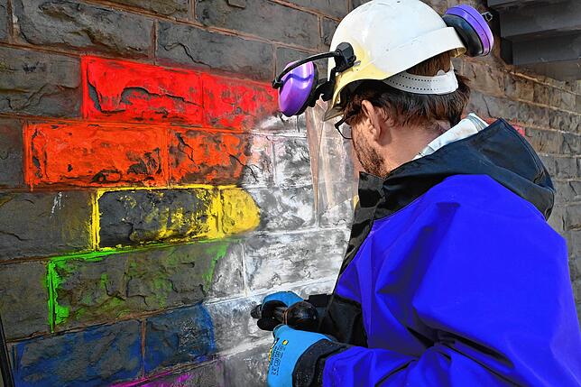 Dass die Farbe auf Sandstein aufgetragen ist, macht die Reinigung herausfordernd, da die Farbe in die Poren gesickert ist. Deshalb muss ...