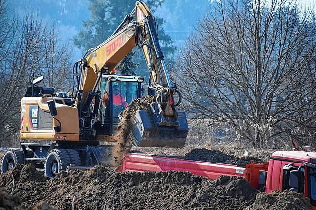 Mathias Erath lädt mit dem Bagger Erdmaterial auf einen Lastwagen.