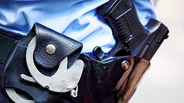 Ein Polizist mit Handschellen und Pistole am Gürtel. Polizisten haben 2024 im Dienst deutlich mehr Menschen erschossen als in den Jahren ...