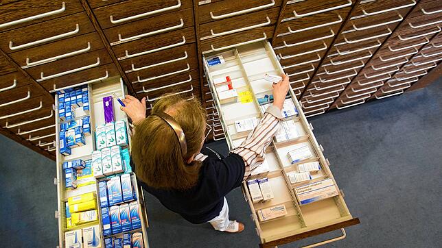 Eine Apothekerin steht vor einer ausgezogenen Medikamenten-Schublade. Die Liste der Lieferengpässe wird immer länger.
