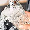 Am Wasserhahn in einer Küche wird ein Trinkglas mit Leitungswasser befüllt. (Symbolbild)