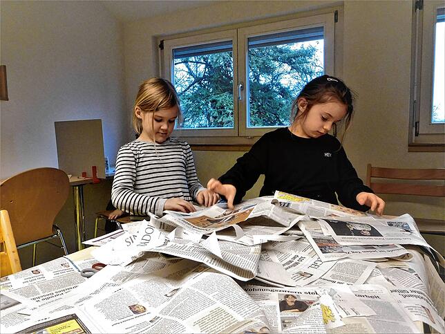 Eva und Pia beim Blättern durch die Zeitung: Gerade die farbenfrohen Bilder und die gemalten Karikaturen fallen ihnen besonders in die ...