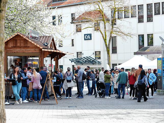 Unter blühenden Bäumen lockt der Essensstand viele Menschen an.