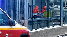 Feuerwehrleute in Schutzanzügen untersuchen den Container, in dem die ungeplante chemische Reaktion auftrat.