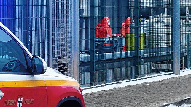 Feuerwehrleute in Schutzanzügen untersuchen den Container, in dem die ungeplante chemische Reaktion auftrat.