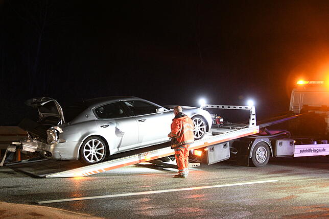 Ein Fahrzeug ist bei dem Unfall von einem Autoanhänger gefallen. Ein Abschleppwagen nimmt das Auto mit.