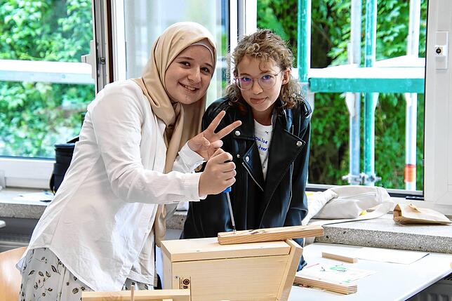 Samira Abdulhakimava (12) und Luisa Loutner (12) helfen einander beim Bauen der Nistkästen.