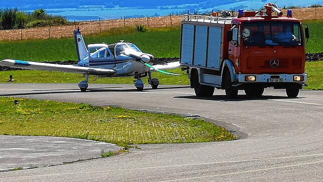 Nach der Notlandung konnte der Pilot nicht mehr aus eigener Motorkraft zum Hangar rollen. Das Feuerwehrfahrzeug des Flugplatzes wurde ...