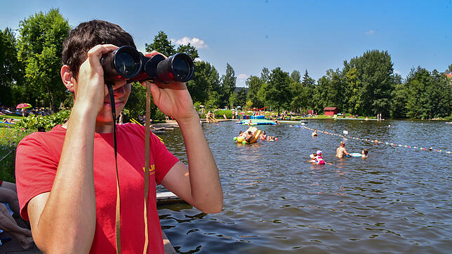 Niklas Flaig kontrolliert mit dem Fernglas den Badebetrieb auf dem Wasser im Klosterweiher: Für die ehrenamtlichen DLRG-Retter ist es ...