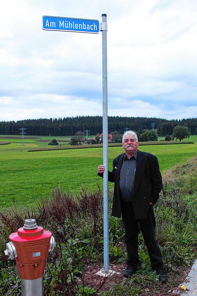 Ortsvorsteher Horst Kritzer mit dem frisch montierten Straßenschild „Am Mühlenbach“ am Neubaugebiet.