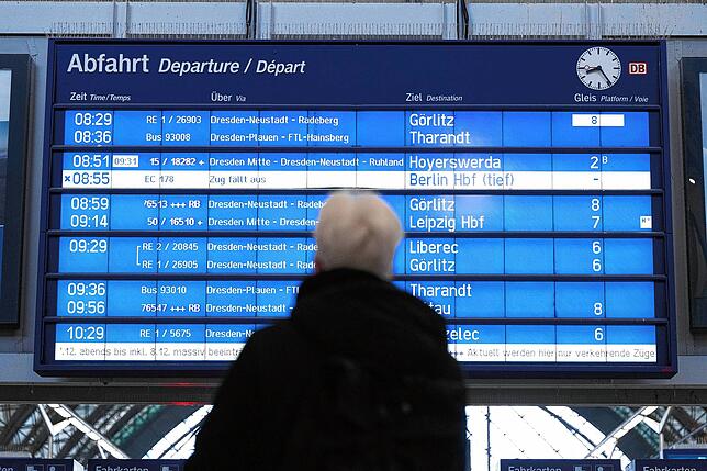 Ein Mann steht im Dresdner Hauptbahnhof vor einer digitalen Anzeigetafel. Wenn ein Zug fünf Minuten zu spät kommt, gilt er in ...