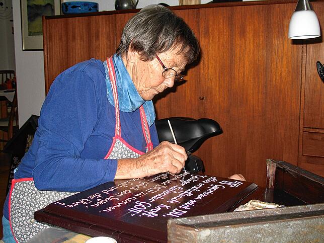 2018: Sorgfältig malt Inge Klawiter in ihrer Werkstatt die einzelnen Buchstaben der Franziskus-Verse mit Acryllack bei der Renovierung ...