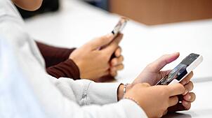 Schüler benutzen während eines Vortrags im Biologieunterricht über die Anwendungen von Künstlicher Intelligenz (KI) ihr Smartphone im ...