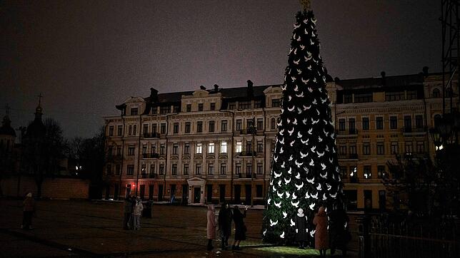 Menschen fotografieren in Kiew einen Weihnachtsbaum, der mit Friedenstauben geschmückt ist.