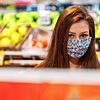 Eine Auszubildende in einem Supermarkt und trägt eine vermutlich selbst genähte Schutzmaske. Damit kann die Gefahr, andere zu ...