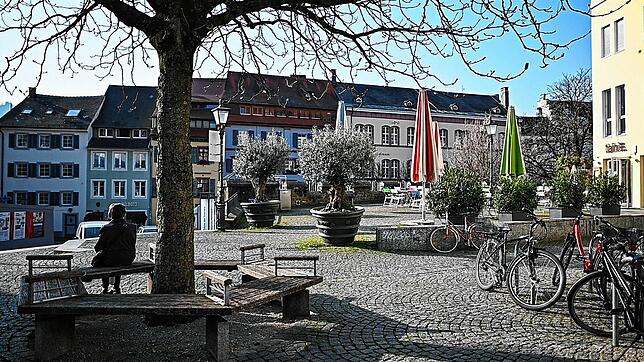 Eine Frau sitzt am leeren Augustinerplatz unter einem Baum. Die Stadt Freiburg erlässt wegen der Corona-Pandemie eine Ausgangssperre für ...
