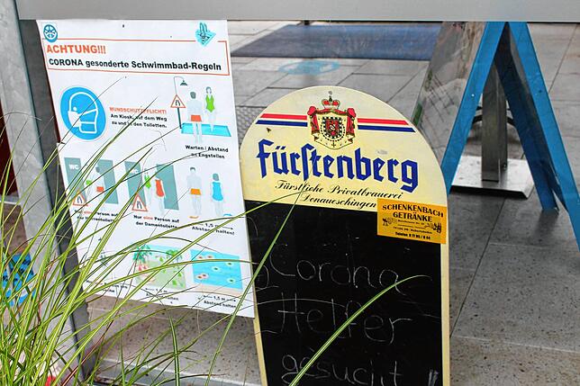 Schon am Eingang des Freibads werden die Besucher mit den Corona-Regeln vertraut gemacht. Und Helfer gesucht.