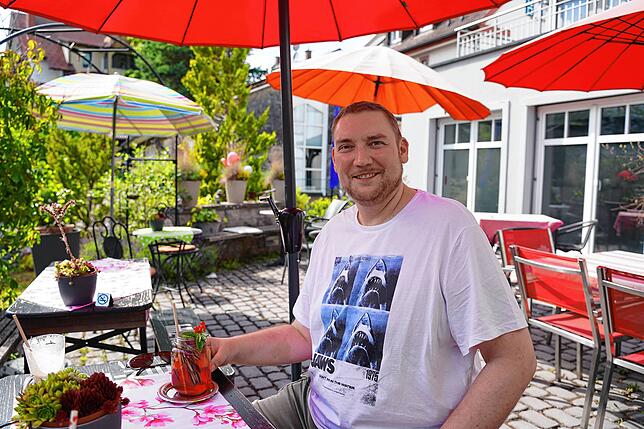 Heiko Lechleitner genießt eine Holunder-Rhabarber-Limonade auf der Terrasse im Mein Sahnehäubchen in Königsfeld.