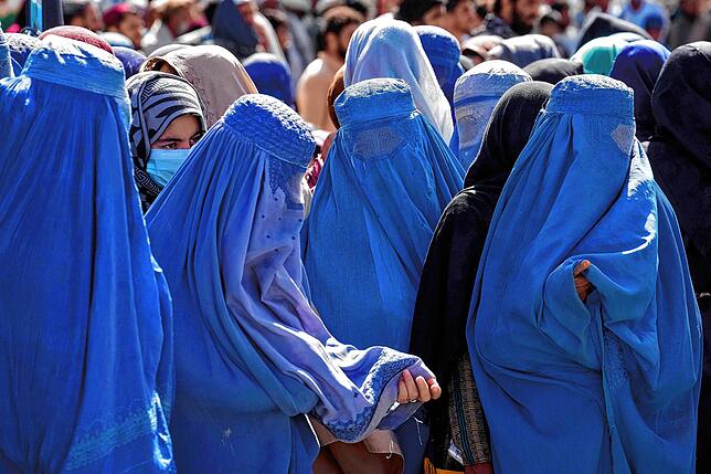 Vollverschleierung ist wieder Pflicht: Frauen warten an einer Verteilstelle in Kabul auf Lebensmittelrationen, die von einer humanitären ...