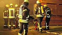 Die Atemschutzträger der Rohrdorfer Feuerwehr machen mit den Entlüftungsgeräten die Lagerhalle wieder rauchfrei. Bild: Karl Mägerle