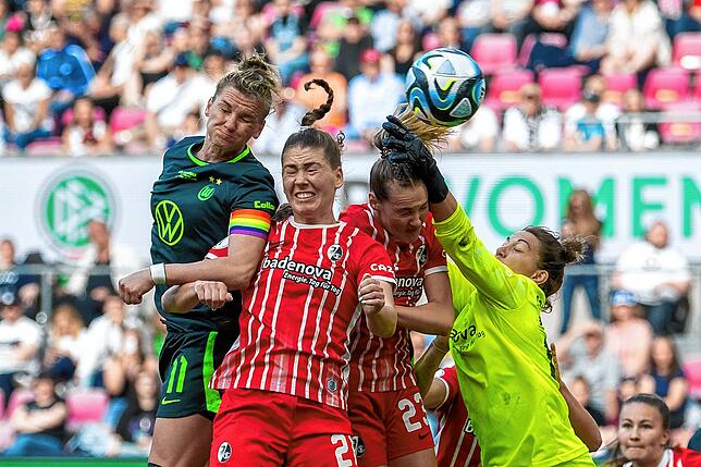 Wolfsburgs Alexandra Popp (l-r) macht im Zweikampf mit Freiburgs Samantha Steuerwald und Freiburgs Torfrau Marie Müller das Tor zum 3:1.
