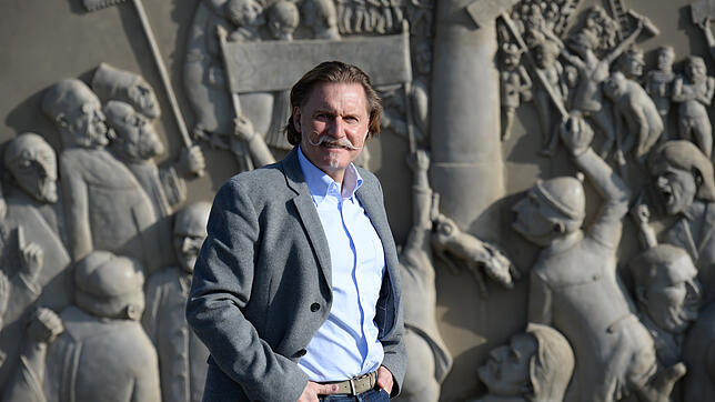Ingo Lenßen posiert in Bodman-Ludwigshafen vor einem Wandrelief des Künstlers Peter Lenk. Lenßen lebt und arbeitet am Bodensee als ...