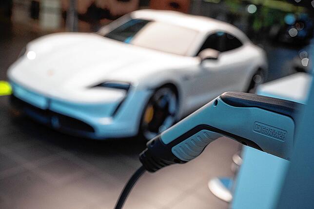 Ein elektrischer Porsche Taycan Turbo S steht im Porsche Zentrum Stuttgart hinter einer angedeuteten Ladesäule. Der Sportwagenbauer ...