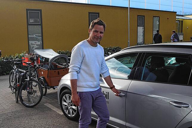 Vom Lastenrad im Hintergrund steigt Jan Otte am Parkplatz an der Schänzlehalle um auf ein Carsharing-Auto.