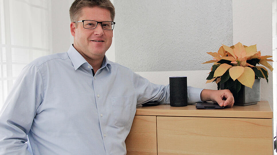 Jörg Putschbach steht in seinem Wohnzimmer neben einem der vier Echo-Sprachassistenten im Haus.