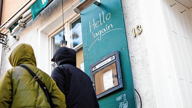 Passanten gehen an einem Gasthaus vorüber, an dessen Tafel der Schriftzug &bdquo;Hello again&ldquo; zu lesen ist. Bund und Länder wollen ...
