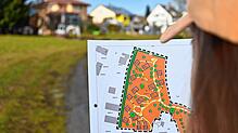 Eine Passantin betrachtet die Pläne für das Feriendorf auf dem Geländer der Familie Oßwald. Gäste sind hier schon lange willkommen. Nun ...