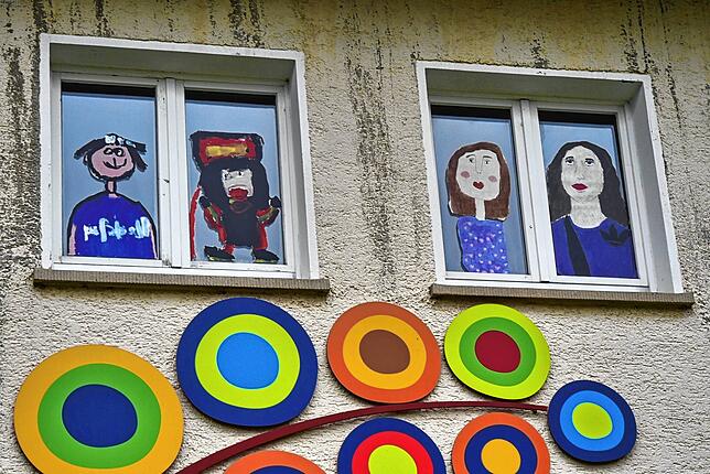 An etlichen Fenster grüßen die fröhlichen Porträts von Schülerinnen und Schülern.