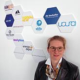 Christina Groll leitet das städtische Gründungszentrum „Farm“. Hinter ihr sind die Logos jener Firmen zu sehen, die von dort ...