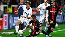 Freiburgs Ritsu D·an (l) und Leverkusens Alejandro Grimaldo (M) kämpfen um den Ball. Rechts läuft Leverkusens Exequiel Palacios.